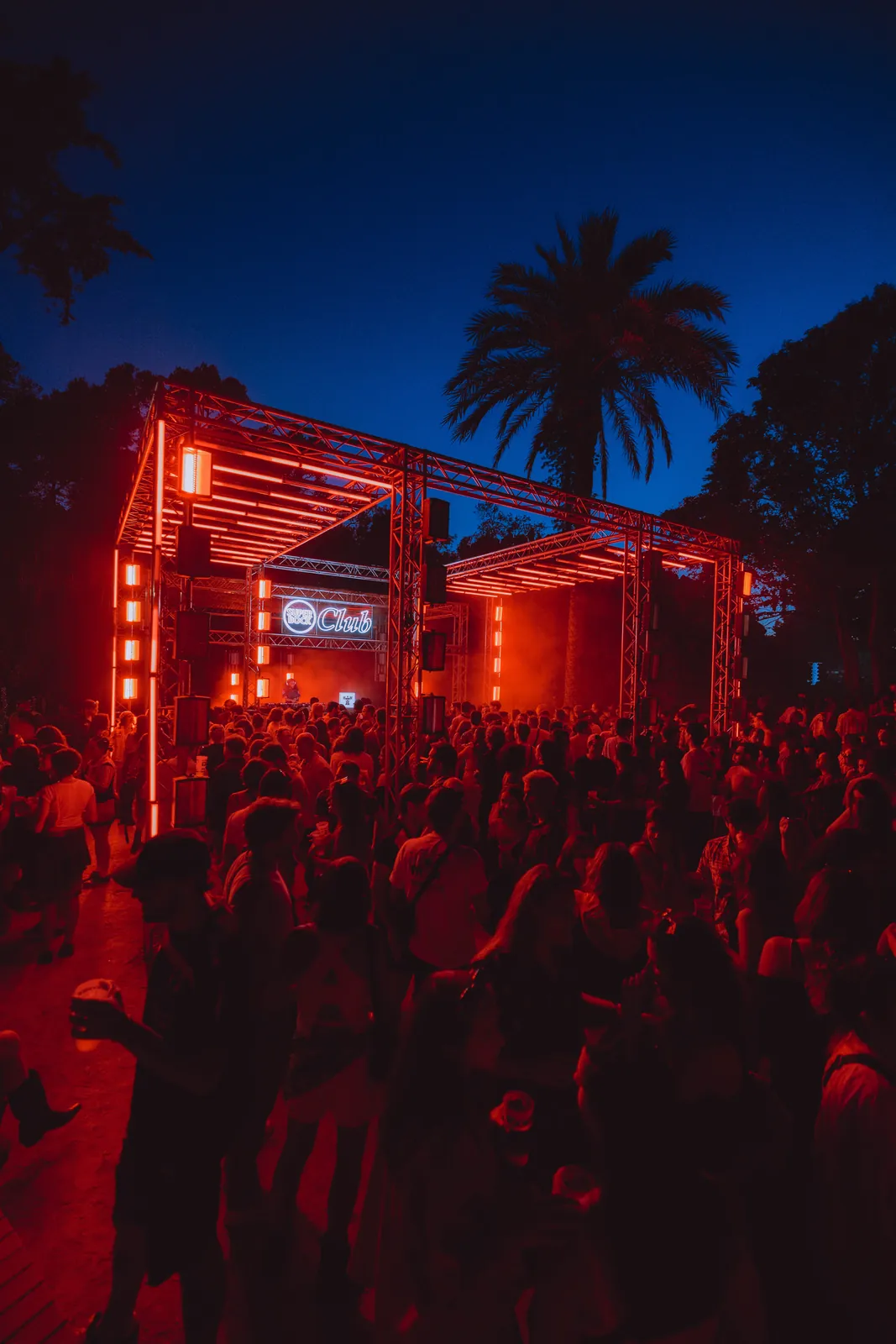 Palco em luz vermelha ao anoitecer, com palmeira